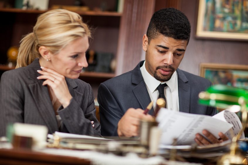 Female sitting with a male disability attorney looking over paperwork